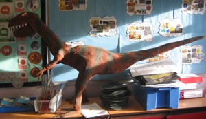 A Velociraptor sculpture on display in a classroom.