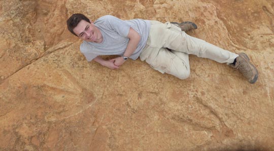 Dr Fabien Knoll provides a scale for the dinosaur footprints.