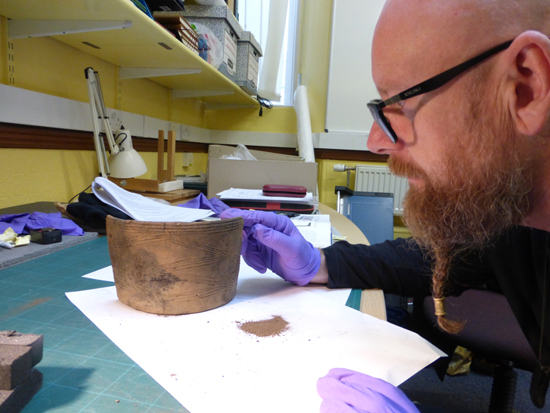 Dr Mike Cooper examines a prehistoric clay pot.